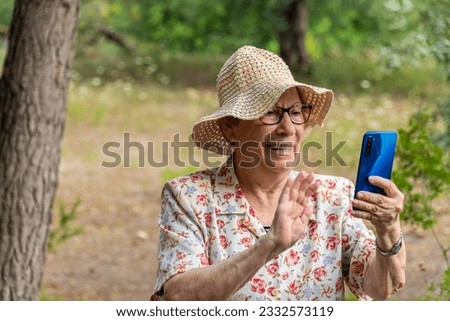 Cute senior woman with a hat takes a selfie outdoors.