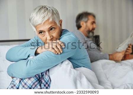 Portrait of unhappy senior woman or couple during or after arguing while sitting on bed, married elderly couple discussing in bed, or a health problem, mature woman being in pain Royalty-Free Stock Photo #2332590093