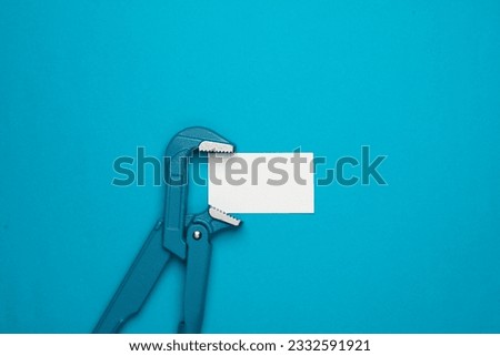 Metal adjustable wrench with business card on a blue background.