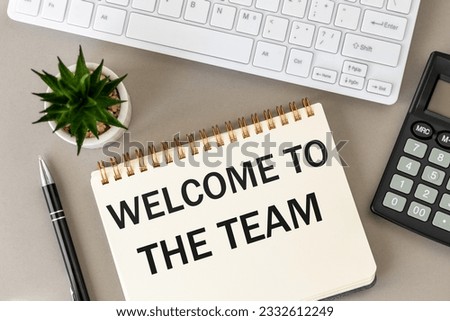 Welcome to the team, Welcome lettering on the desk, Business concept, Building community in the company, Beautiful gray background, office equipment and a notebook with a slogan
