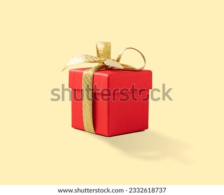 Red present box with gold ribbon on a yellow background. Gift concept for a birthday, wedding or new year. Copy space. Royalty-Free Stock Photo #2332618737