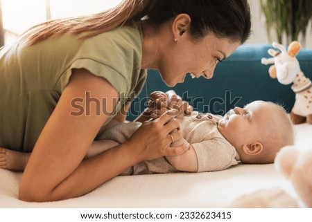 Young mother enjoying and having fun with her cute baby at home.