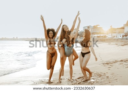 Happy female friends piggybacking each other on the beach, women smiling cheerfully while having fun on coastline. Best friends enjoying their vacation together