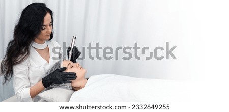 cosmetologist making mesotherapy injection with dermapen on face for rejuvenation. Anti-aging treatment and face lift in cosmetology clinic. medical procedure with Electric pen. banner with copy space Royalty-Free Stock Photo #2332649255
