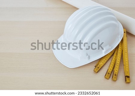 Construction tools and a white hard hat with a measuring stick, paper house building plan on a wooden work table copy space for text Royalty-Free Stock Photo #2332652061