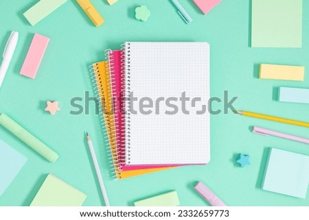 Back to school background. Flat lay, top view of school accessories, notebook, pens on isolated light green table background. School stationery on desk. Copyspace
