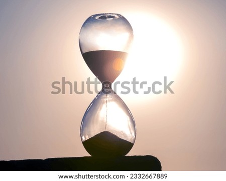 Hourglass counts the length of time against the background of the evening sun. The concept of the fluidity of life time in the universe. time and light