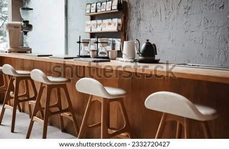 Seat and wooden counter with coffee equipment on counter bar and wooden shelf on rough cement wall. design for cafe or home Royalty-Free Stock Photo #2332720427