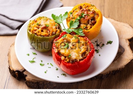 Stuffed peppers, halves of peppers stuffed with rice, dried tomatoes, herbs and cheese in a baking dish on a blue wooden table, top view. (Turkish name; biber dolmasi) Royalty-Free Stock Photo #2332760639