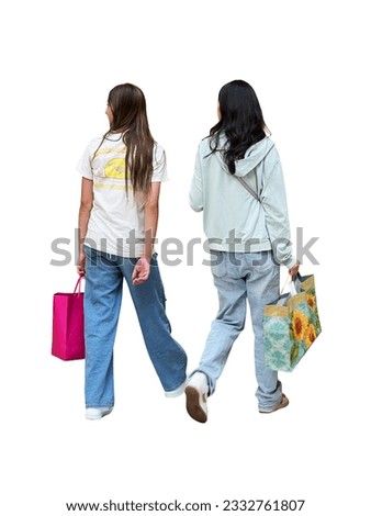 Two young girls walking through a shopping mall with shopping in fashionable stylish clothes step forward. Back view of cut out isolated teenagers