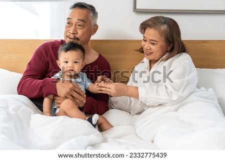 Portrait of happy love asian grandfather with grandmother playing with asian baby on bed, senior, insurance.Big family love with their laughing grandparents smiling together.Family and togetherness
