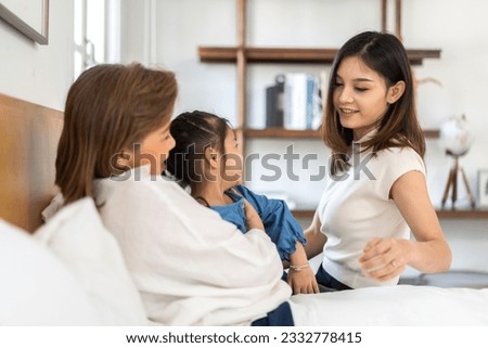 Portrait of happy love asian grandmother and asian little cute girl play and enjoy relax on bed at home.senior, insurance, care.Young girl with their laughing grandparents smiling together.Family