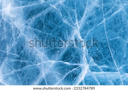 Beautiful winter natural blue ice texture of surface of frozen Baikal Lake in cold day. Nature abstract pattern of white cracks. Winter seasonal background, mock up, flat lay, blank, closeup, top view Royalty-Free Stock Photo #2332784789