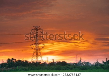 high voltage pole orange sunrise background in the rural fields of Thailand
