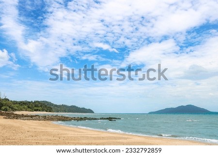 Tropical sandy rocky beach with clear clear blue water under a blue sky with cirrus clouds.