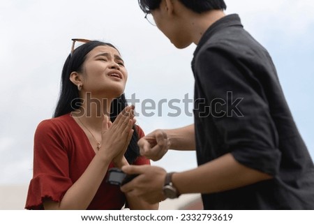 A young woman begs for forgiveness after being caught cheating by her boyfriend over salacious and flirty chats with another man on her cellphone. Royalty-Free Stock Photo #2332793619