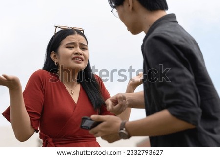 A young woman denies any knowledge after being confronted by her boyfriend over salacious and flirty chats with another man on her cellphone. A desperate cheater in defensive mode. Royalty-Free Stock Photo #2332793627