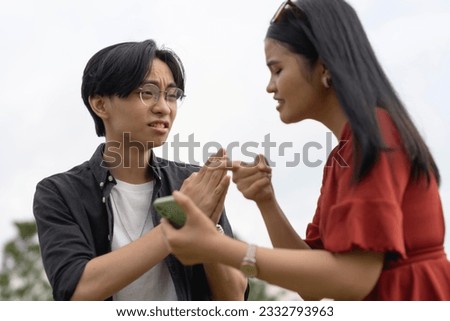A young man asks for a second chance after being confronted by his girlfriend over flirty chats with another woman found on his cellphone. A desperate cheater exposed for infidelity by his partner. Royalty-Free Stock Photo #2332793963