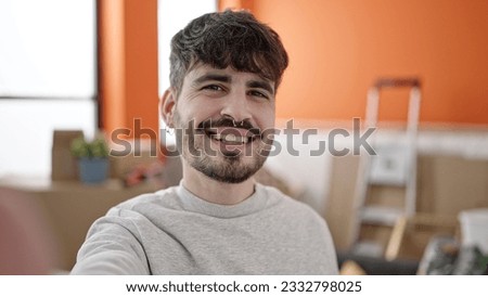 Young hispanic man smiling confident making selfie by camera at new home