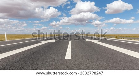 White direction sign on highway pavement under clear sky
