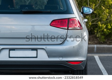 Back bumper and back lights of silver car parked on the street in summer sunny day, rear view. Royalty-Free Stock Photo #2332818549