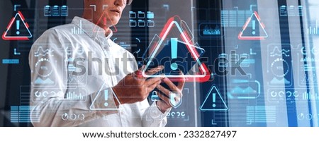 Businessman using tablet in hands, side view. Warning system alert sign hologram and glowing digital security and business infographics, icons and dashboard. Concept of virus and cyber attack Royalty-Free Stock Photo #2332827497