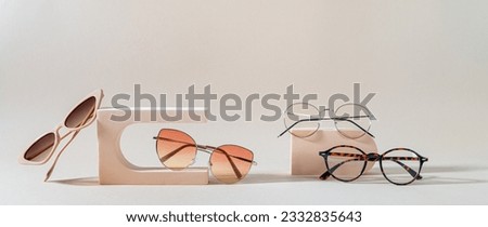 Set of different sunglasses and eyeglasses on podiums on beige background. Summer fashion eyeglasses collection. Sunglasses sale, discount, promotion banner. Minimal style flat lay, copy space Royalty-Free Stock Photo #2332835643