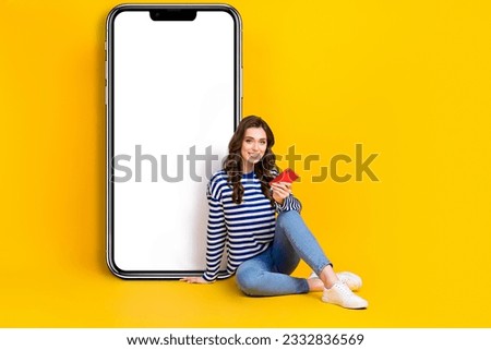 Full size photo of positive girl sit floor use telephone empty space poster isolated on yellow color background