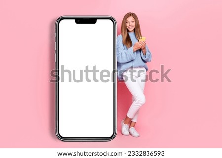 Full length size photo of positive teenager girl wear blue knitted jumper hold phone browsing phone empty space isolated on pink color background