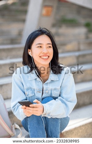 Portrait smiling young woman listening to music with phone and earphones