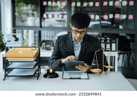 Justice and law concept.Male judge in a courtroom the gavel, working with digital tablet computer.