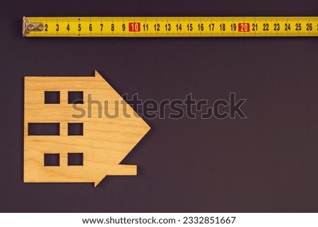 The image of the house on the background. Measurement of the size, tape-measures. The concept of housing, the size of the house. Construction concept
