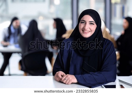 Middle Eastern Arab at office with Emirati Arabic workmates at the background. Emir national wearing Abaya at meeting room Royalty-Free Stock Photo #2332855835