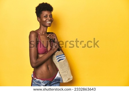 Happy African woman in bikini with beach bag ready for vacation.