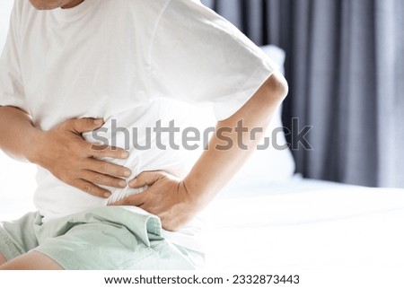 Middle aged man with left abdominal pain,uncomfortable tightness in the abdomen,stomach ache,soreness in belly and difficulty breathing,symptoms of splenomegaly,abnormal enlargement of the spleen Royalty-Free Stock Photo #2332873443