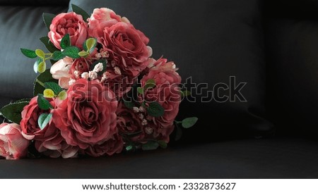 Picture of a bouquet of red roses placed on the sofa in the house.