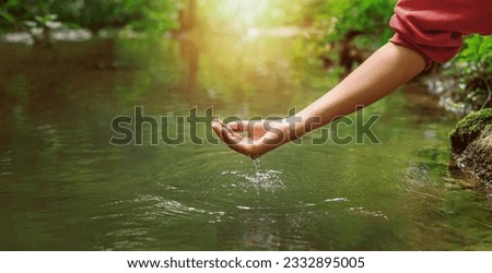 Woman's hand touching water in the midst of nature Royalty-Free Stock Photo #2332895005