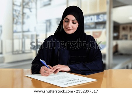 Emarat bank teller or customer signing a contract inside a financial bank. Arab Emirati to sign a paper ideal for business deal or bank loan.