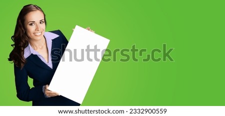 Happy smiling woman in black confident suit showing holding mock up white signboard. Business and advertising concept. Copy space empty free place for text. Green color background.	
