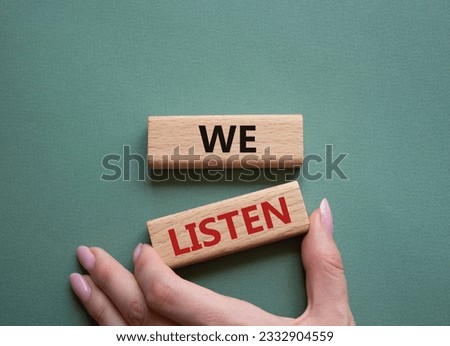 We listen symbol. Wooden blocks with words We listen. Businessman hand. Beautiful grey green background. Business and We listen concept. Copy space.