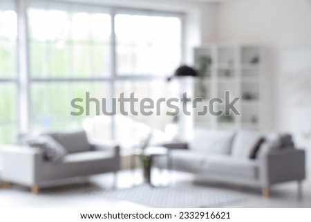 Blurred interior of light living room with grey sofas, coffee table and big window Royalty-Free Stock Photo #2332916621