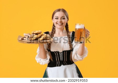 Beautiful Octoberfest waitress with beer and snacks on yellow background Royalty-Free Stock Photo #2332919353
