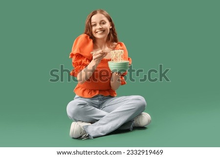 Young woman with bowl of Chinese noodles sitting on green background