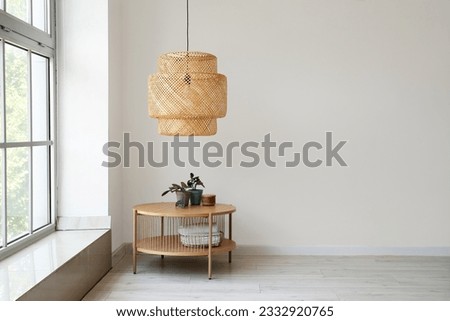 Wooden coffee table with houseplant and wicker lamp near white wall Royalty-Free Stock Photo #2332920765
