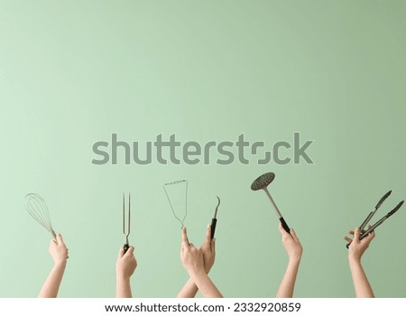 Women with kitchen utensils on green background Royalty-Free Stock Photo #2332920859