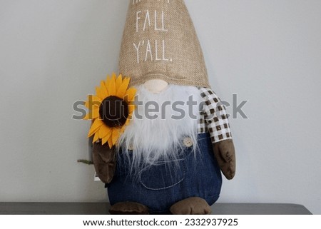The isolated image of a stuffed gnome sitting on a table. His hat reads "Happy Fall Y'all".