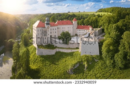Aerial view of Pieskowa Skała Renaissance castle, standing on Little Dog's Rock  limestone cliff in the forest valley of river Prądnik. Stone Castle among trees, red roofs, tourist spot in Poland. Royalty-Free Stock Photo #2332940059