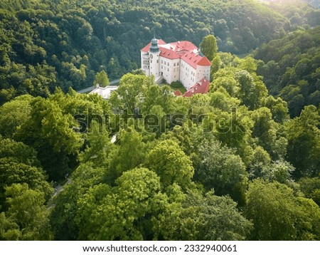 Traveling Poland concept: Aerial view of Pieskowa Skała Renaissance castle, standing on Little Dog's Rock  limestone cliff in the green forest valley of river Prądnik. Summer, sunset, sightseeing. Royalty-Free Stock Photo #2332940061