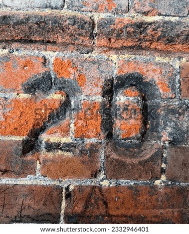 Number 20 carved on an old brick wall. The number markers were chased into the crumbling brick in a coal store. The surface of the chiselled numbers has been filled with coal dust and soot.