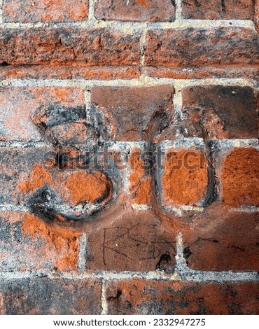 Number 30 carved on an old brick wall. The number markers were chased into the crumbling brick in a coal store. The surface of the chiselled numbers has been filled with coal dust and soot.